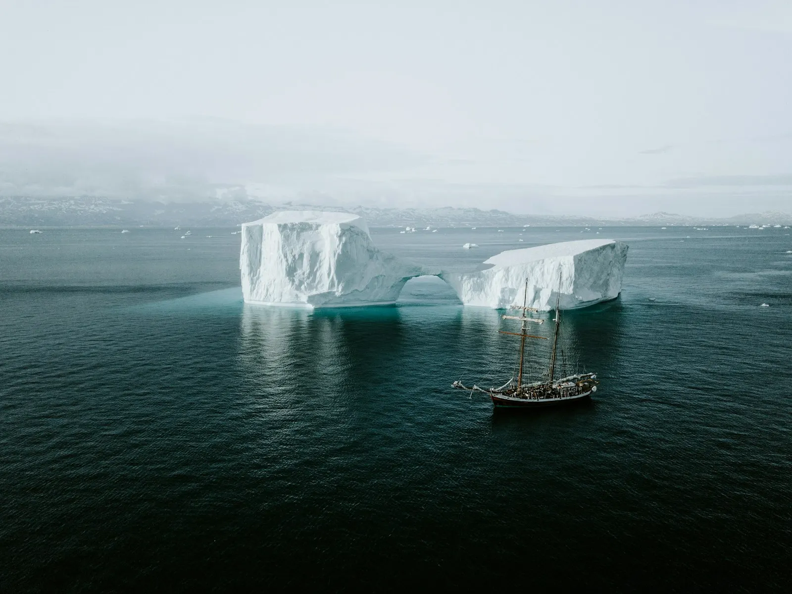 Northwest Passage — schooner sailing past an iceberg in the Arctic